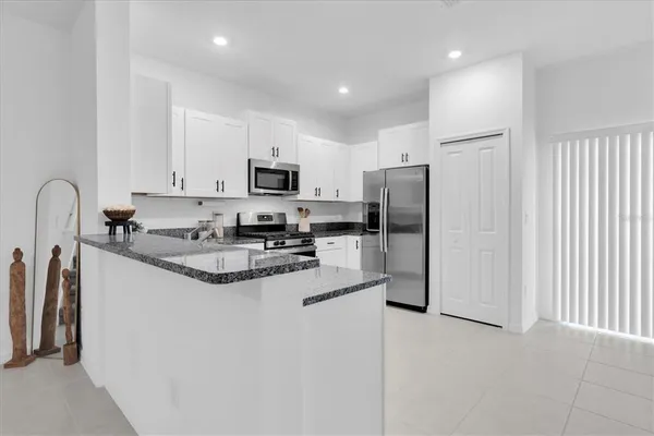 a kitchen with stainless steel appliances granite countertop a stove top oven a sink a dining table and chairs