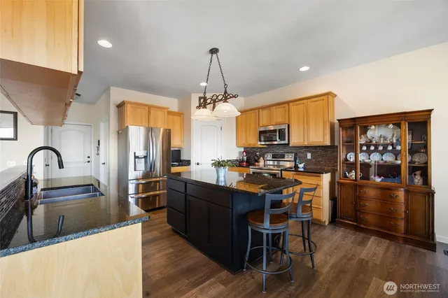 a kitchen with stainless steel appliances a stove a refrigerator a sink dishwasher and a dining table with wooden floor