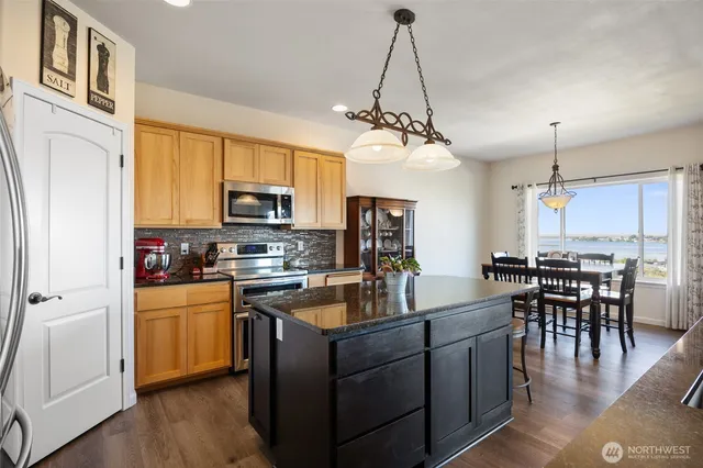 a kitchen with a refrigerator a stove top oven a sink dishwasher a dining table and chairs with wooden floor