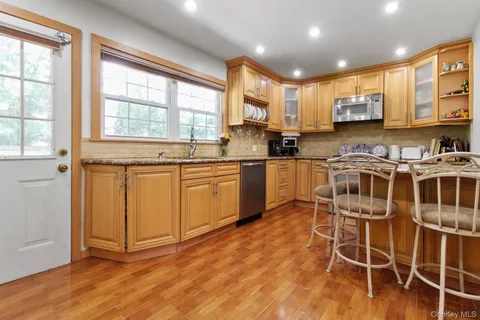 a kitchen with stainless steel appliances granite countertop a stove top oven a sink a dining table and chairs