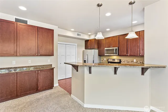 a kitchen with stainless steel appliances granite countertop a refrigerator stove and sink