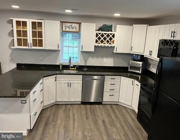 a kitchen with granite countertop white cabinets and black appliances