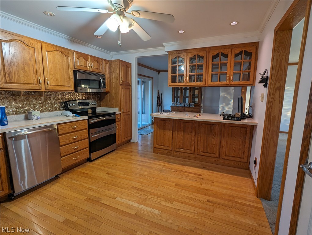 53154 Key Bellaire Road Bellaire, OH 43906 - Photo 8 of 43 Kitchen with crown molding, appliances with stainless steel finishes, light hardwood / wood-style floors, ceiling fan, and tasteful backsplash