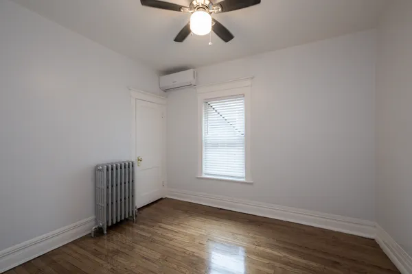 an empty room with wooden floor chandelier fan and windows