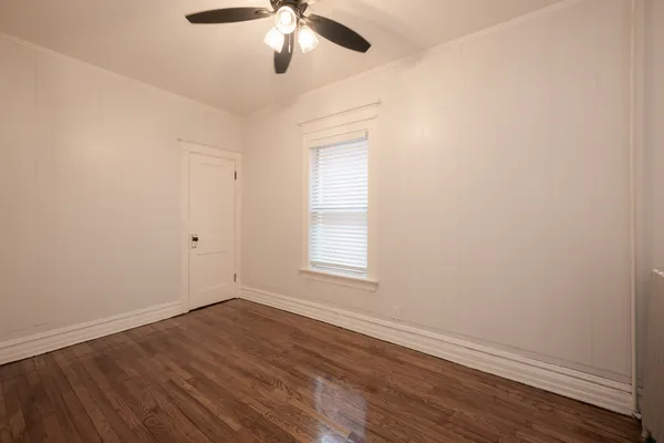 an empty room with wooden floor fan and windows