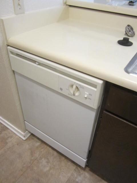 12480 Abrams Road, Unit 521 Dallas, TX 75243 - Photo 15 of 26 White built-in dishwasher with a light-toned laminate countertop, dark wood-finish cabinetry, and patterned flooring