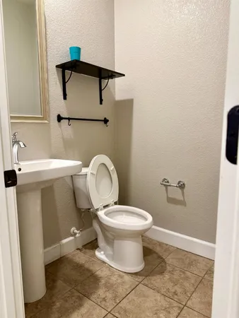 a view of a hallway to a room with wooden floor and a bathroom