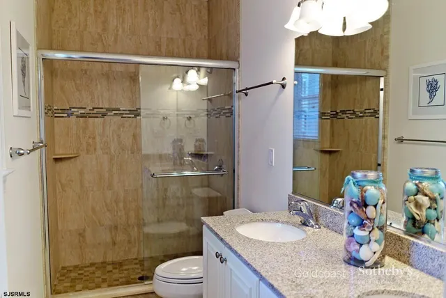 a bathroom with a granite countertop sink a toilet and shower