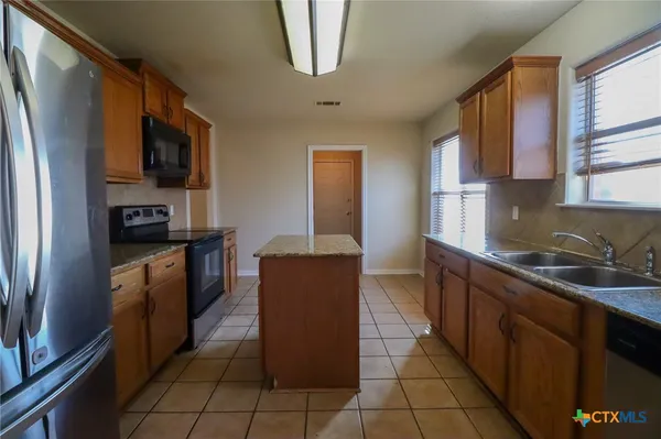 a kitchen with stainless steel appliances granite countertop a refrigerator a stove top oven a sink and dishwasher