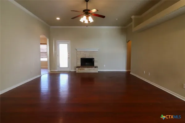 a view of a room with wooden floor fireplace and windows
