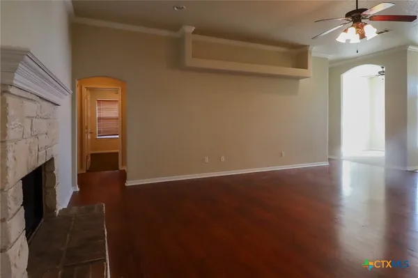 a view of an empty room with wooden floor and a fireplace