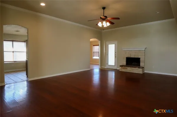 an empty room with wooden floor chandelier and windows