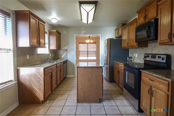 a kitchen with stainless steel appliances granite countertop a refrigerator and a stove top oven