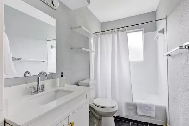 a bathroom with a granite countertop sink toilet and shower