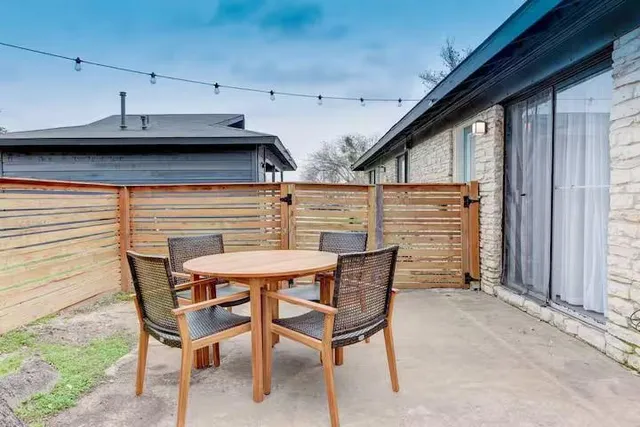 a backyard of a house with large trees and wooden fence