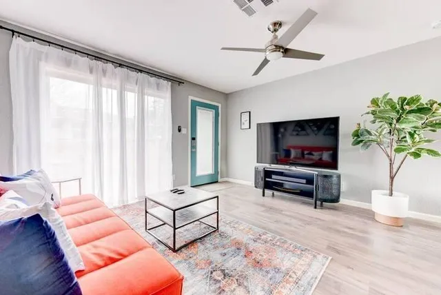 a living room with furniture a flat screen tv and a large window