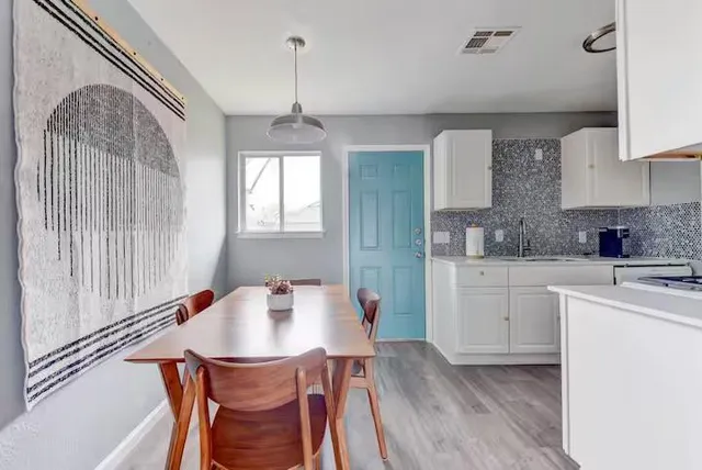 a kitchen with stainless steel appliances granite countertop a sink dishwasher a microwave oven a stove with white cabinets and wooden floor