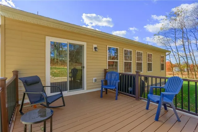 a view of a patio with couches and table and chairs with wooden floor and fence