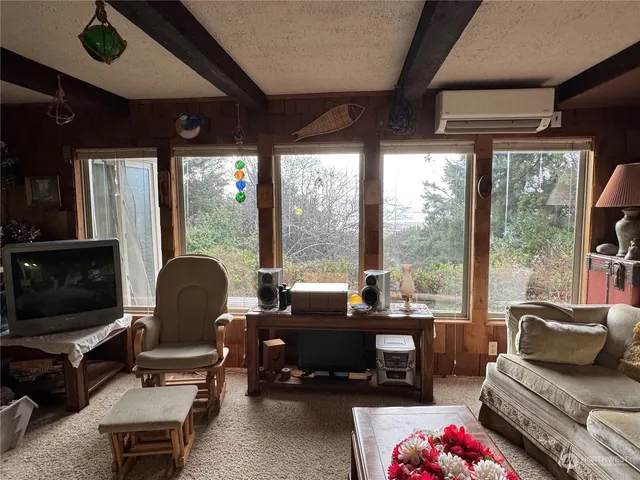 a living room with furniture a flat screen tv and floor to ceiling window