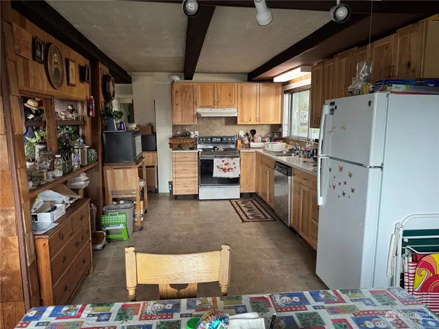 a kitchen with stainless steel appliances granite countertop a refrigerator oven stove a sink dishwasher and a dining table with wooden floor