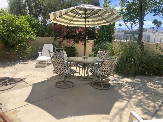200 East Racquet Club Road, Unit 19 Palm Springs, CA 92262 - Photo 13 of 21 a view of a patio with table and chairs under an umbrella