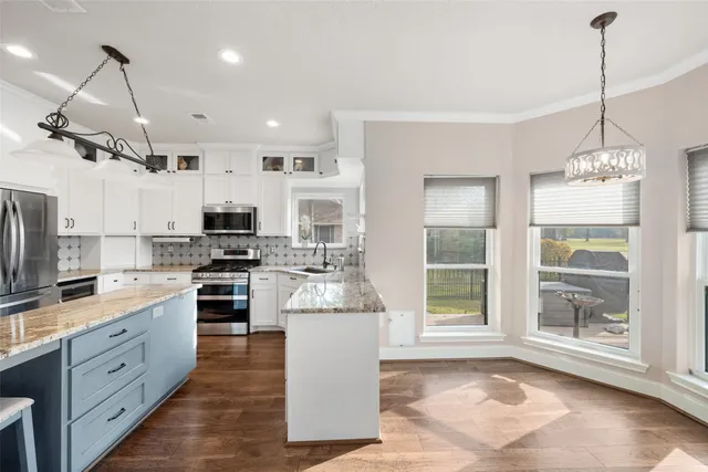 a kitchen with stainless steel appliances kitchen island granite countertop a sink stove and refrigerator