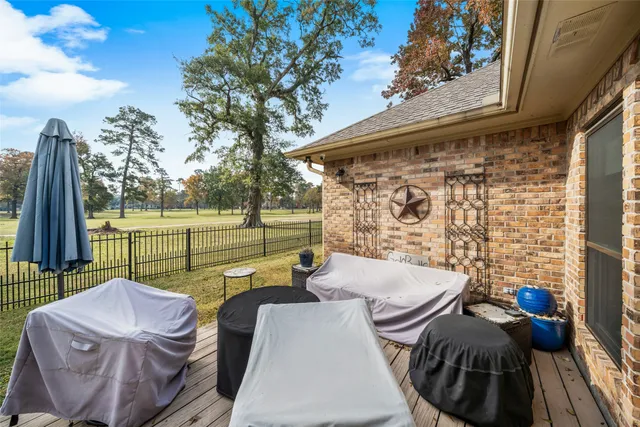 a backyard of a house with table and chairs potted plants and a large tree