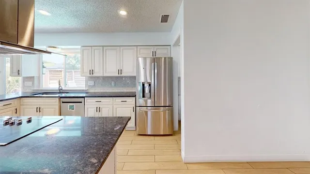 a kitchen with stainless steel appliances granite countertop a sink and a refrigerator