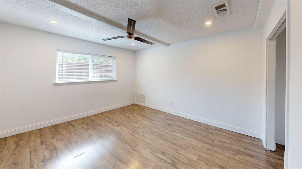 2131 Blossom Lane Richardson, TX 75081 - Photo 8 of 22 an empty room with wooden floor ceiling fan and windows