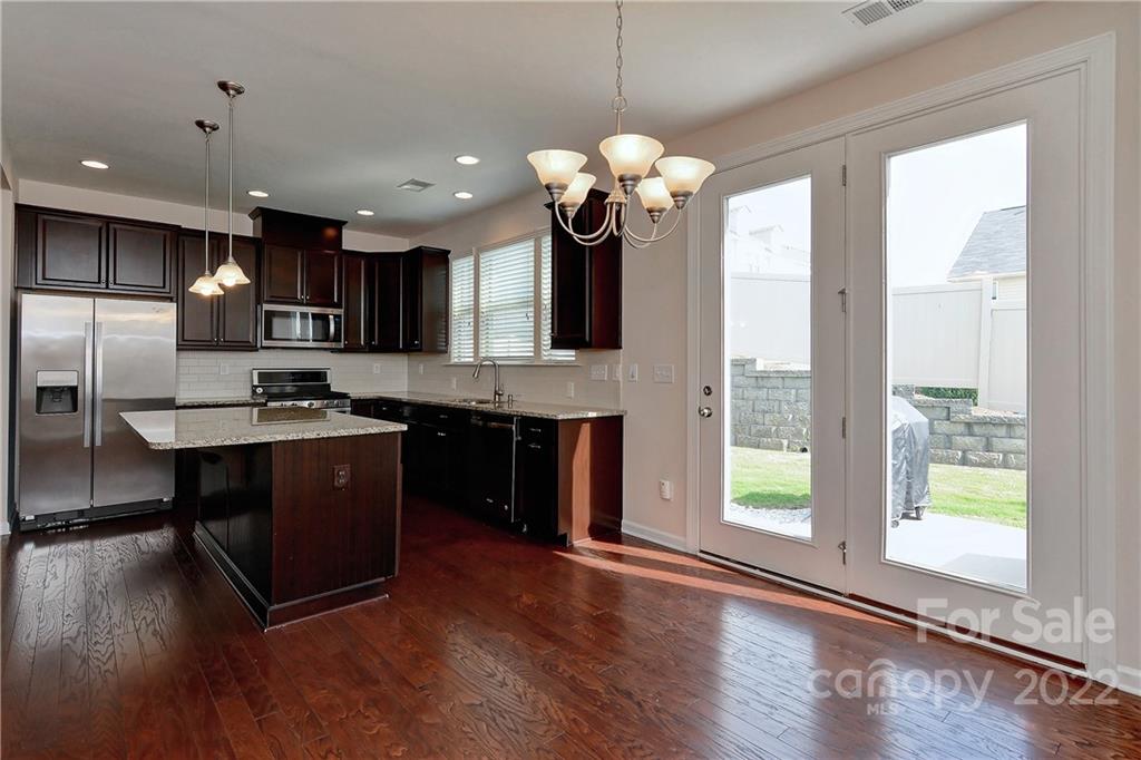 1110 Roderick Drive Fort Mill, SC 29708 - Photo 12 of 37 a kitchen with kitchen island granite countertop a stove a sink a refrigerator and a dining table with wooden floor