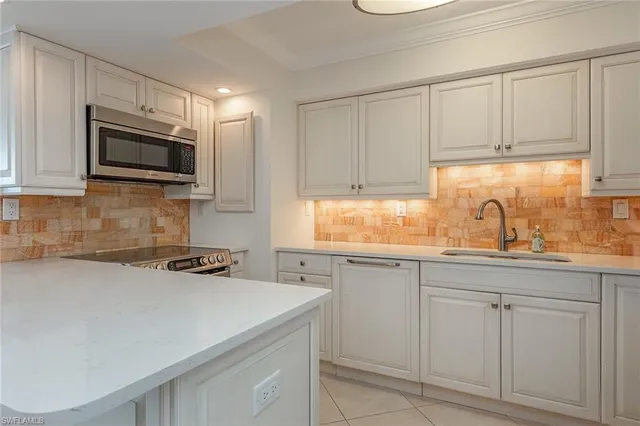 a kitchen with white cabinets and sink