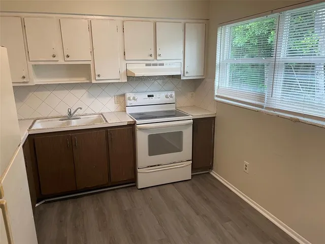 a kitchen with stainless steel appliances granite countertop a stove a sink and white cabinets