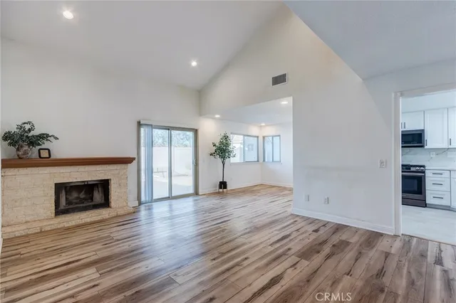 an empty room with wooden floor a fireplace and windows