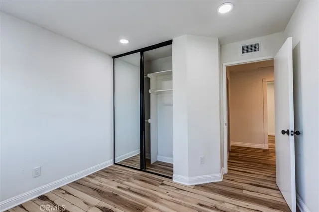 a view of a hallway with wooden floor and closet area
