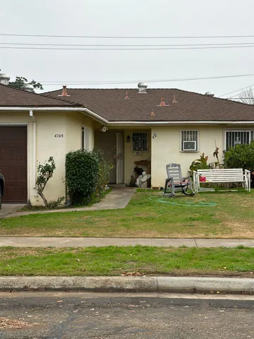 a front view of a house with a yard and potted plants