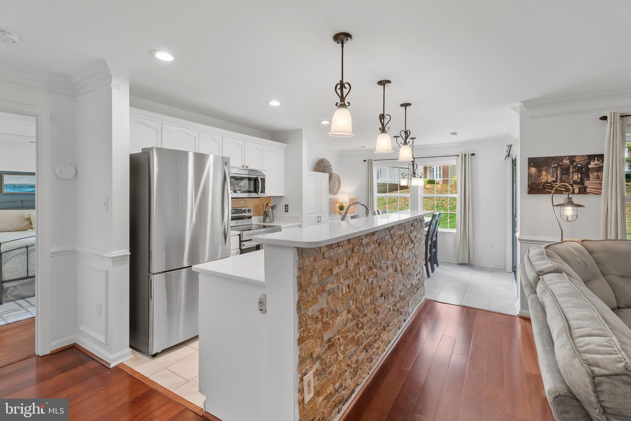 2406 Dominion Drive, Unit 1B Frederick, MD 21702 - Photo 7 of 30 a large kitchen with stainless steel appliances kitchen island granite countertop a refrigerator and a wooden floor