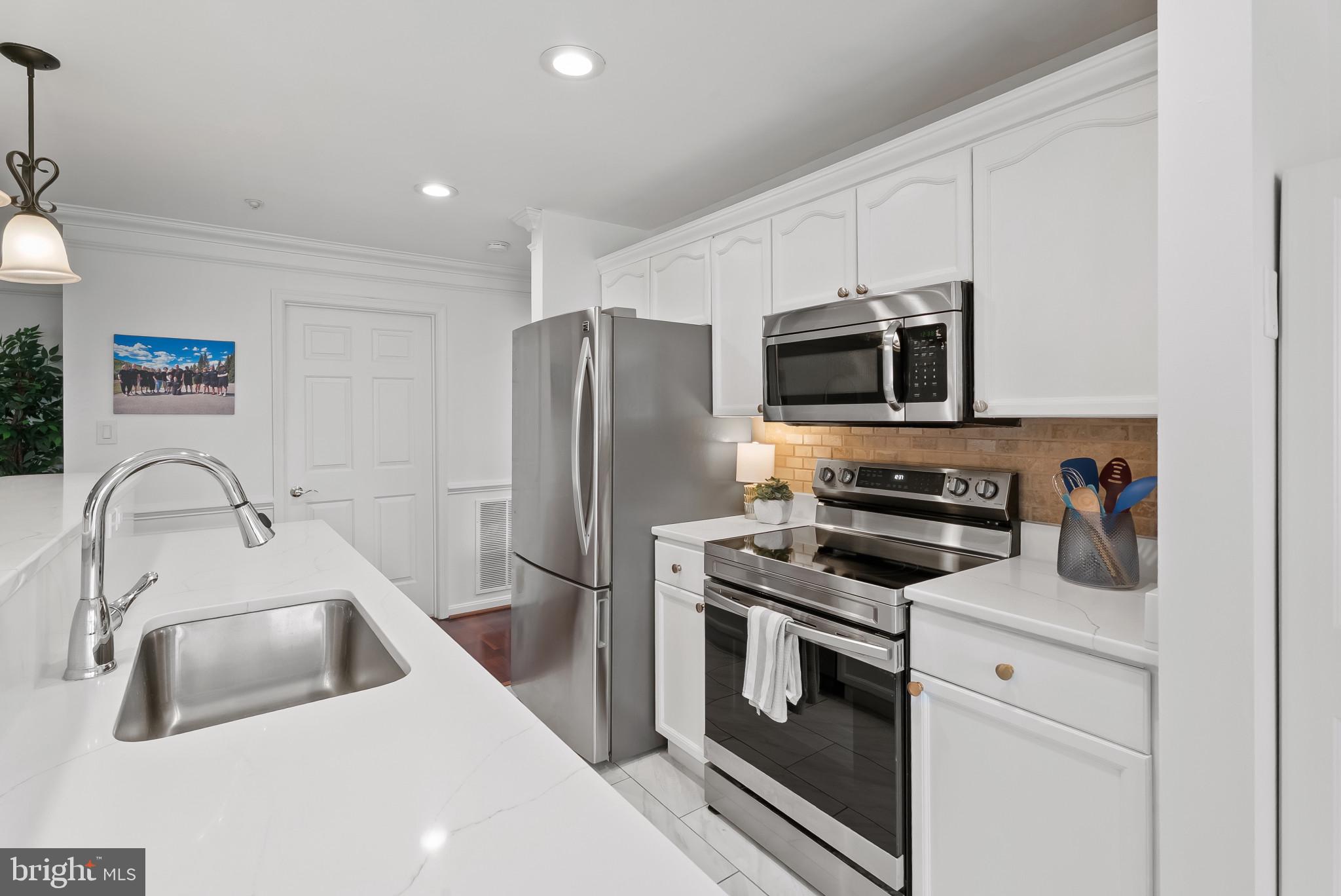 2406 Dominion Drive, Unit 1B Frederick, MD 21702 - Photo 8 of 30 a kitchen with stainless steel appliances a stove a sink a microwave a refrigerator and cabinets