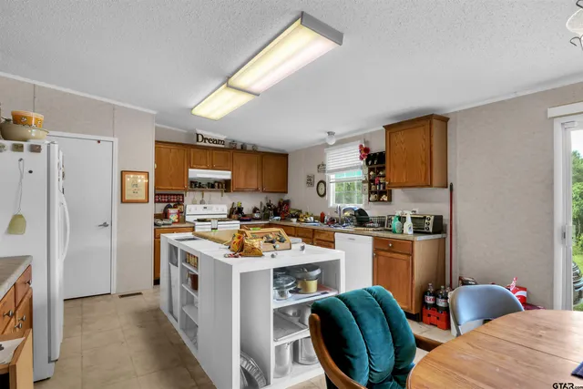 a view of kitchen with stainless steel appliances granite countertop a stove top oven a sink dishwasher and a refrigerator with wooden cabinets