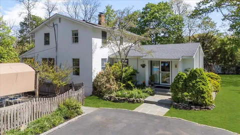 a view of a white house with a yard and potted plants