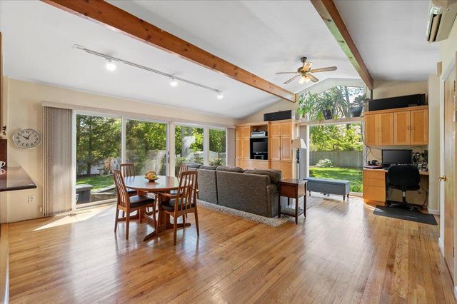 a dining room with wooden floor and large windows