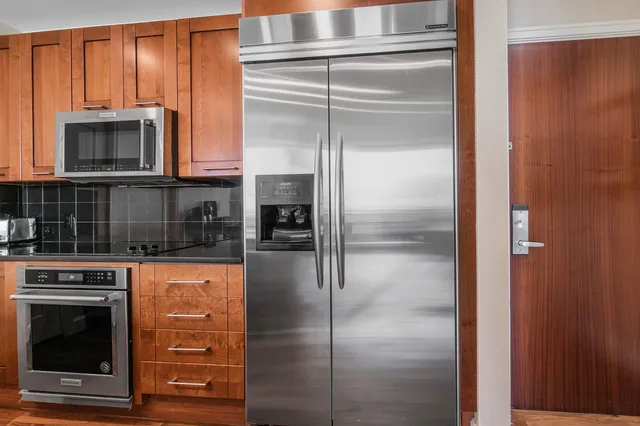 a kitchen with stainless steel appliances granite countertop a refrigerator and a stove top oven