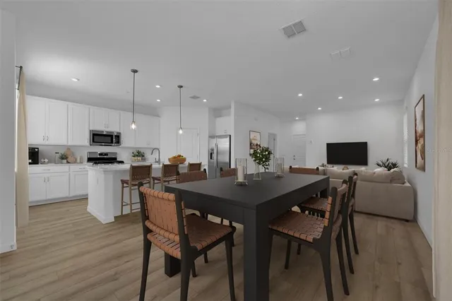 a kitchen with a dining table chairs and wooden floor