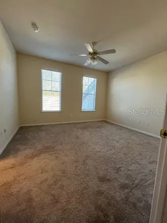 an empty room with windows and ceiling fan view