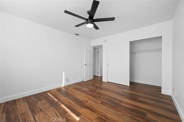 a view of a room with wooden floor and a ceiling fan