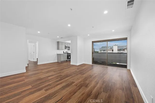 a room with stainless steel appliances wooden floors and kitchen view