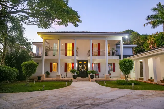 a front view of a house with a yard and potted plants