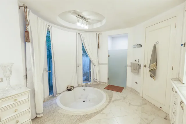 a spacious bedroom with a bed chandelier and a window