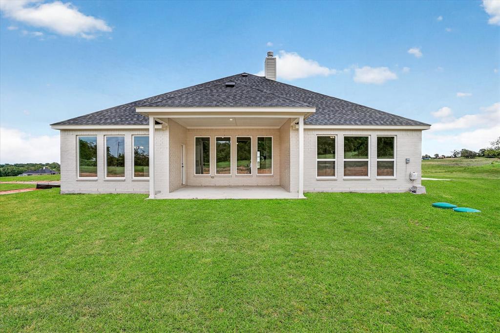 317 Skeen Peak Springtown, TX 76082 - Photo 31 of 31 Expansive rear facade featuring a covered patio, multiple large windows, and a shingle roof