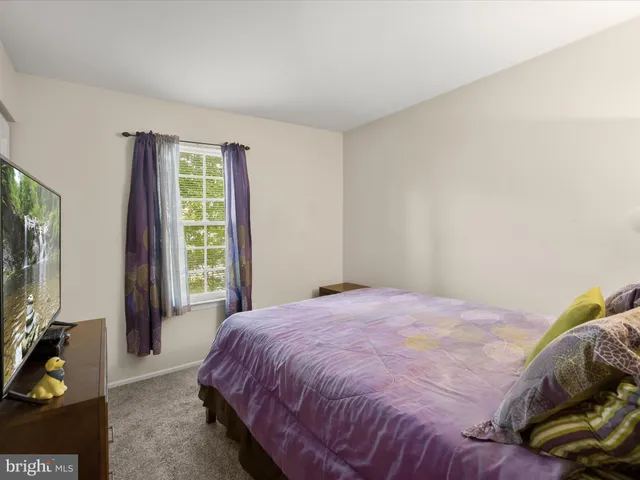 a bedroom with a bed flat screen tv and a window