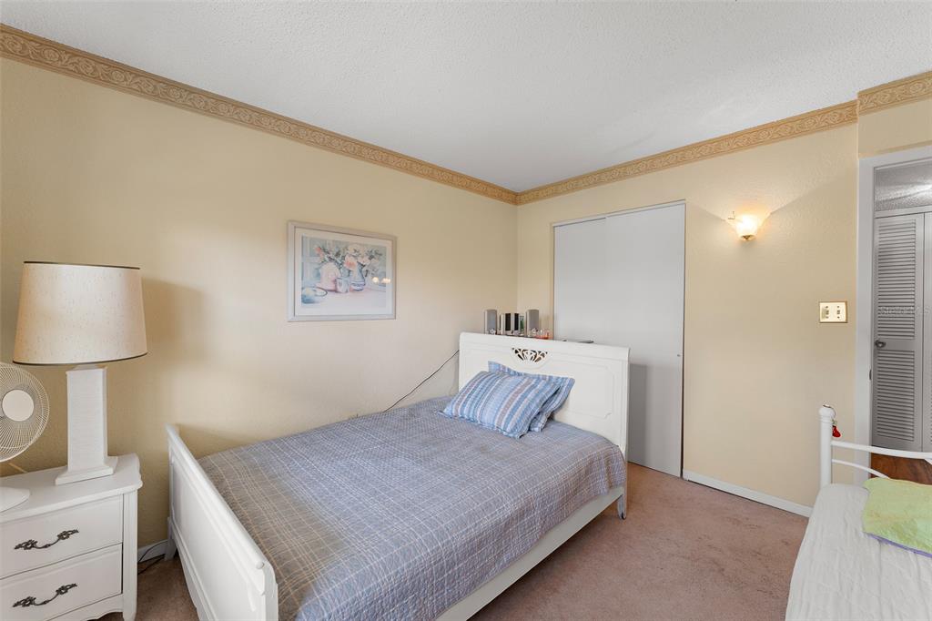 4746 Azalea Drive, Unit 105C New Port Richey, FL 34652 - Photo 18 of 27 a bedroom with a bed and a lamp on dresser